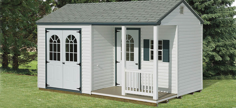 a frame shed with white vinyl siding and porch